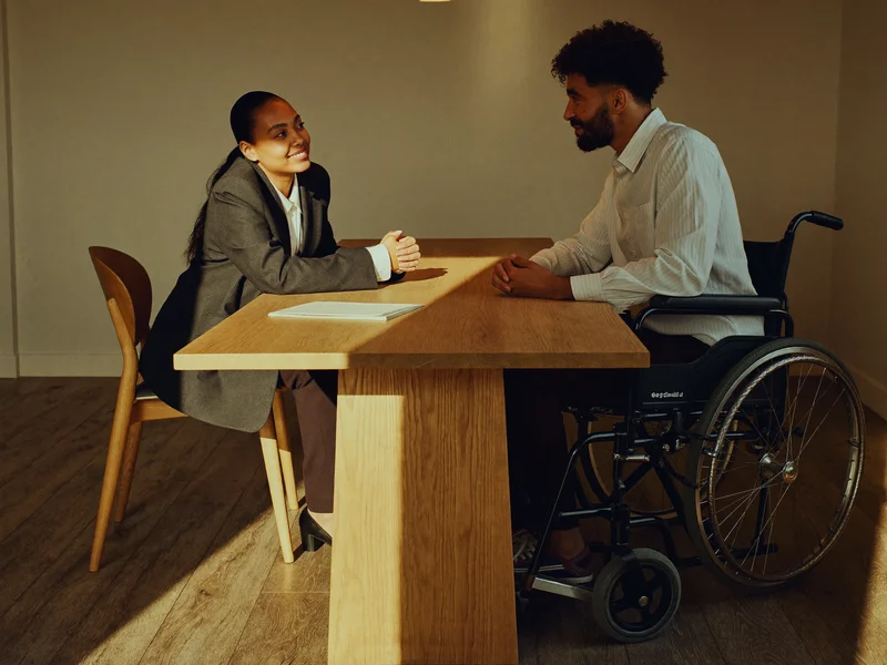 Illustration of an adviser and wheelchair user talking across a table